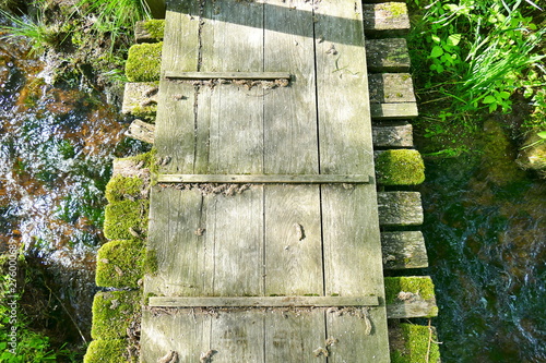 Little aged wooden bridge over a stream from bird's perspective