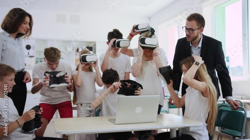 Group of multi-aged classmates using VR headsets educating with future technologies in a class. Teacher and students having an amazin lesson together. photo