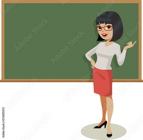 Young female teacher gestures in front of a traditional blackboard.