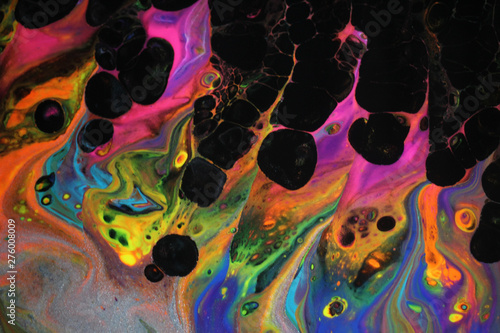 Abstract acrylic pour painting in vibrant retro neon colors and black cells popping up which creates the flame effect.