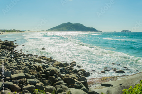 Praia com rochas e vegetação banhada por um mar azul em um dia de Sol photo