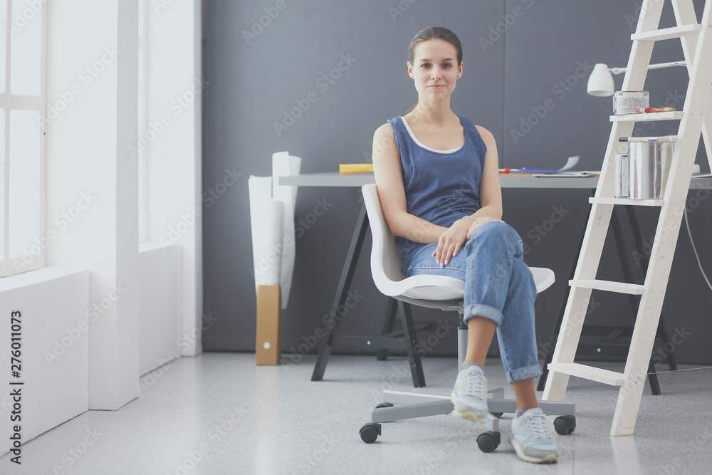 Young woman sitting at the desk with instruments, plan and laptop. Young woman sitting at the desk with instruments, plan and laptop.