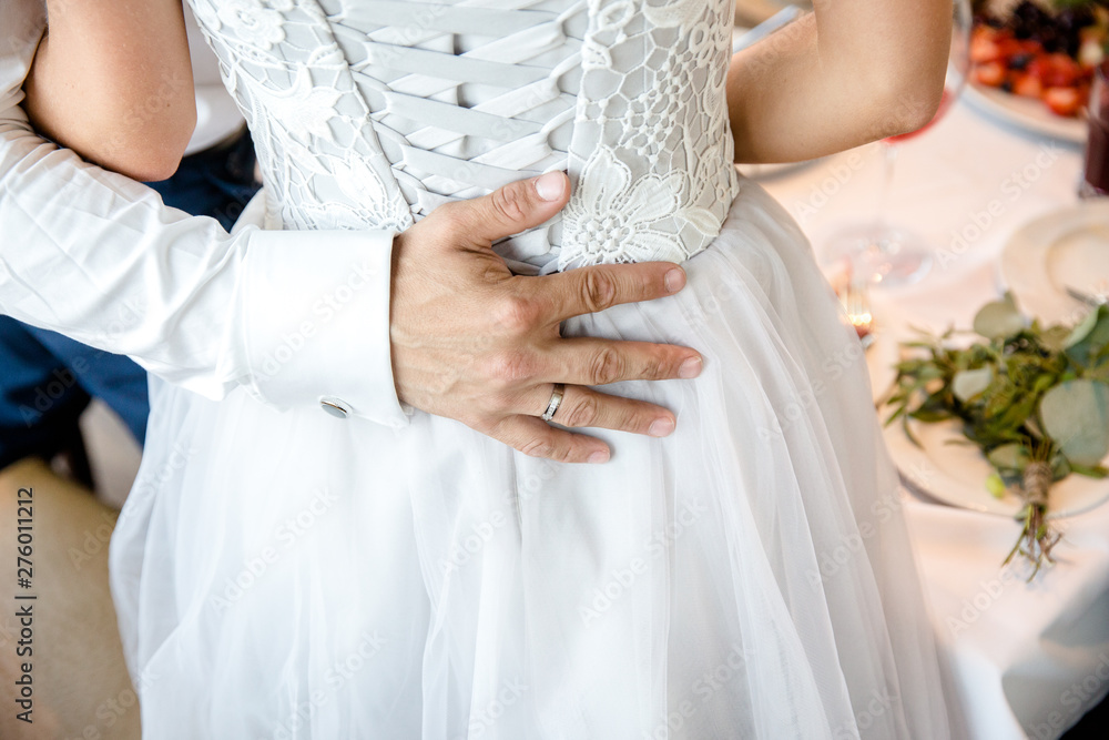 The groom hugs the bride. The hand of the groom on the back of the bride. The groom hugs the bride. The hand of the groom on the back of the bride.