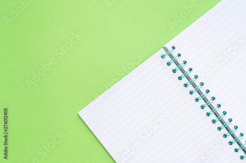 Open Spiral ruled notepad on spring green background. Flat lay with copy space for back to school or education test and craft or message concept