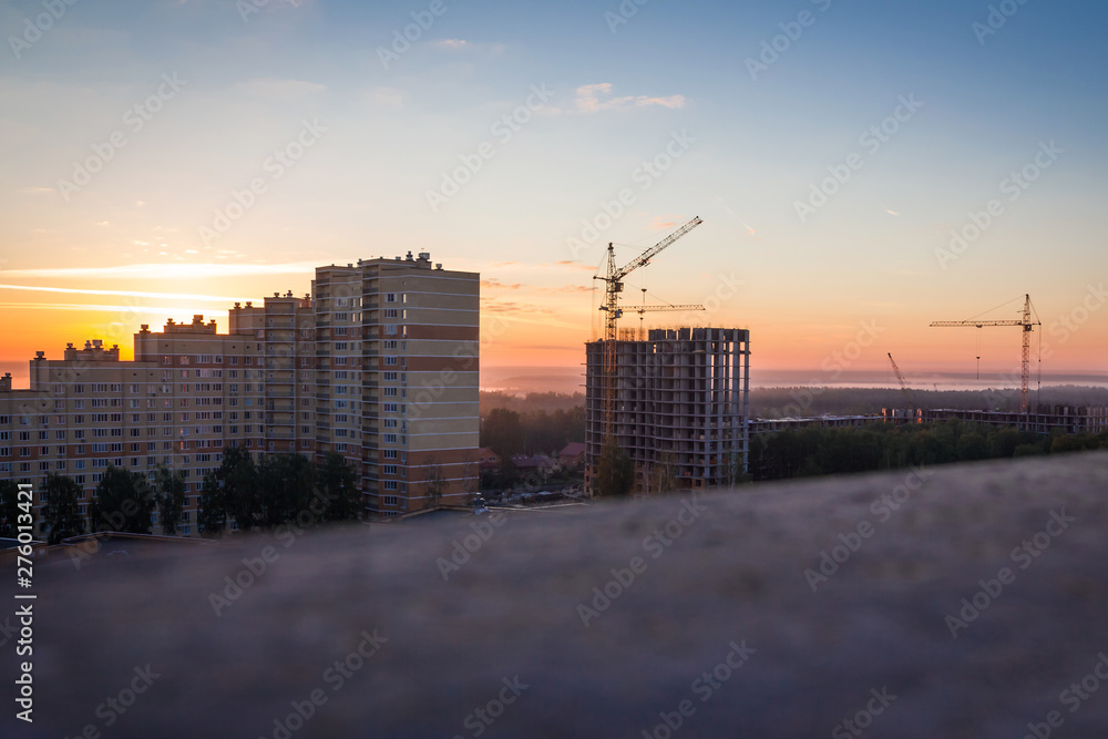 Cranes building new building construction on the sunrise background