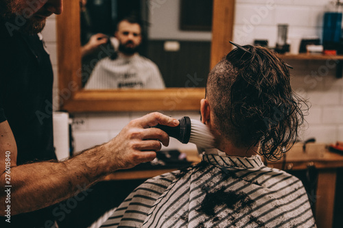 Process of haircuts and stylish styling of long men's hair. Barber making haircut of attractive bearded man in barbershop
