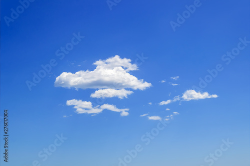 Scenic group of white fluffy cumulus clouds high in the blue summer sky. Different cloud types and atmospheric phenomena. Skyscape.