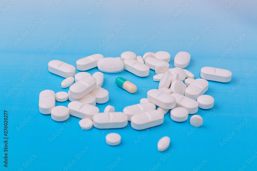 white medicine pill on liht blue background and other in the center