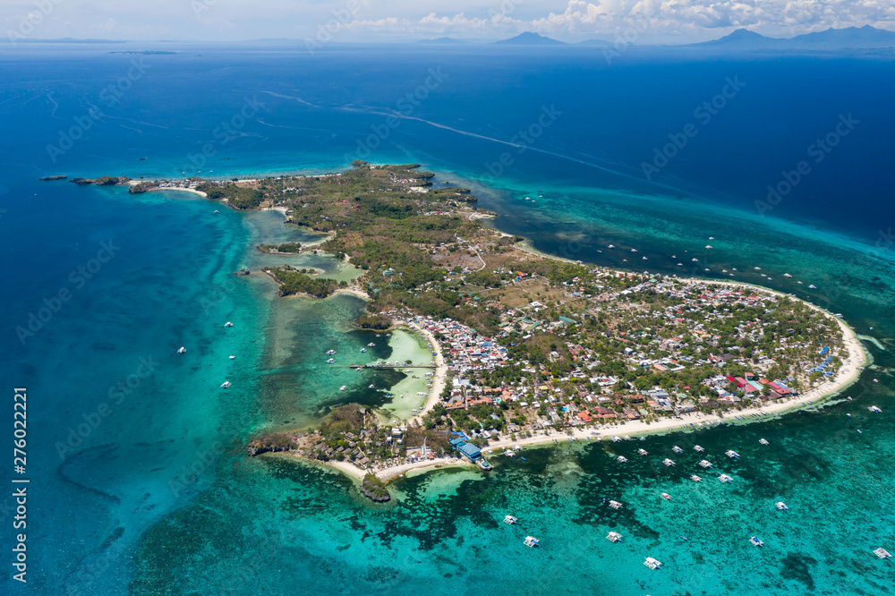 Aerial drone view of a small tropical island and surrounding coral reef (Malapascua)