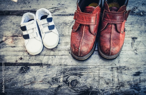 Father boots and baby shoes on wooden background, fathers day. Daddy's boots and baby's shoes, fathers day concept. © Shubby Studio