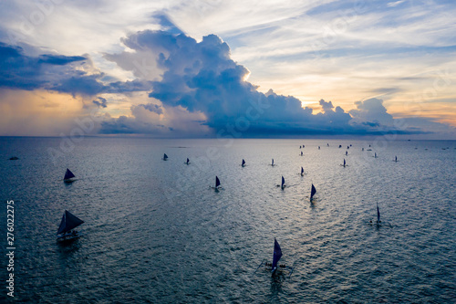 Aerial drone view of large numbers of sailboats at sunset on a tropical ocean (Boracay, Philippines)