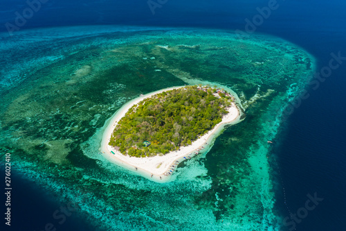 Aerial drone view of a beautiful tropical island surrounded by coral reef and deep ocean (Mantigue Island)
