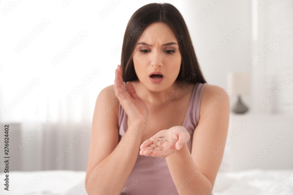 Beautiful woman holding fallen eyelashes in hand indoors Beautiful woman holding fallen eyelashes in hand indoors