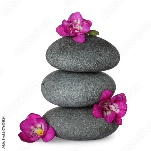 Stack of grey spa stones and fresh flowers isolated on white