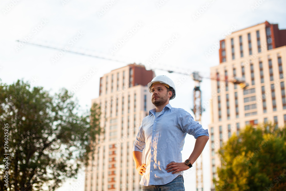 European male engineer builder at construction site. Modern urban architecture. Handsome civil engineer on the background of the building.
