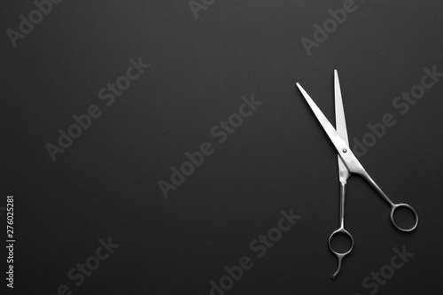 Hairdresser's scissors on dark background, top view. Space for text