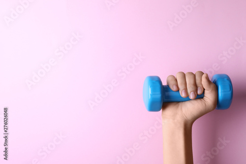 Woman holding vinyl dumbbell on color background, closeup with space for text photo