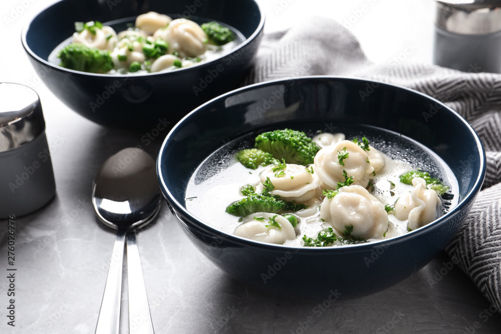 Tasty dumplings in broth served on grey table Tasty dumplings in broth served on grey table