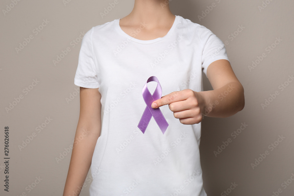 Woman holding purple ribbon on grey background, closeup. Domestic violence awareness Woman holding purple ribbon on grey background, closeup. Domestic violence awareness