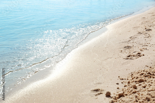 View of sea water and beach sand on sunny summer day