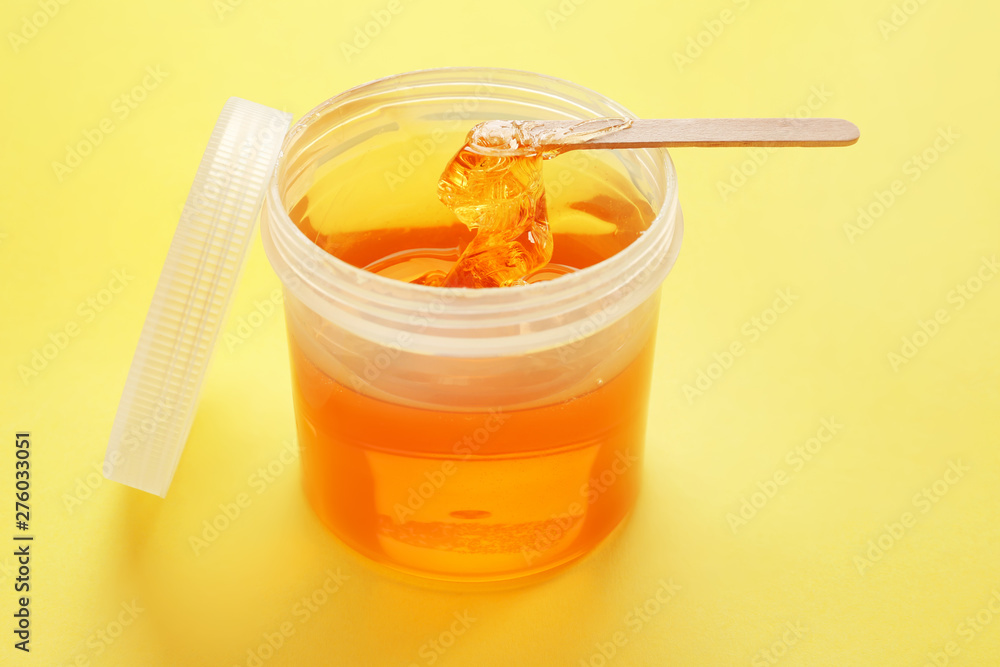 Container with sugaring paste for hair removal on color background Container with sugaring paste for hair removal on color background