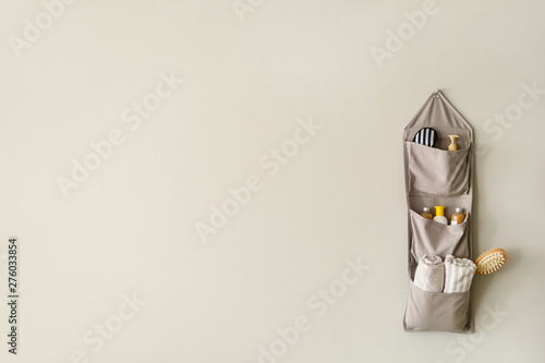 Hanging fabric organizer with bath accessories on light background