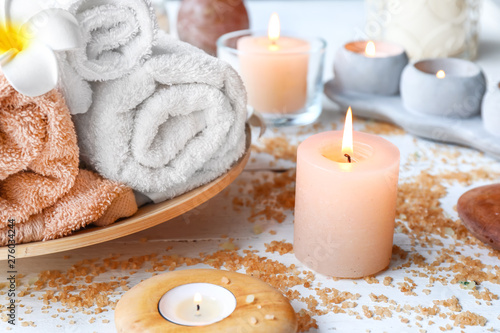 Beautiful spa composition with burning candles, sea salt and towels on table