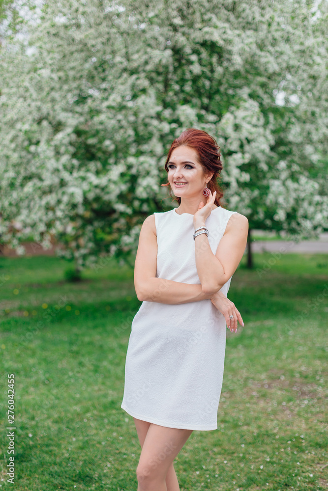 Charming woman wearing beautiful white dress under the apple tree Charming woman wearing beautiful white dress under the apple tree