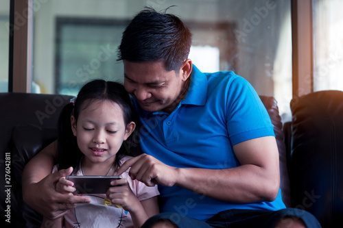 Asian Father and his daughter using smartphone at home