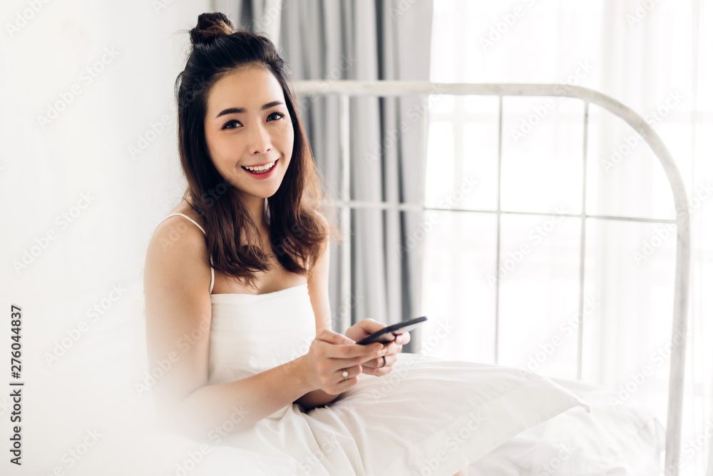 Happy woman relaxing using and talking by smartphone on the bed at home.technology and communication concept Happy woman relaxing using and talking by smartphone on the bed at home.technology and communication concept