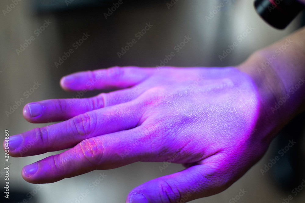 Hands under black UV light to detect glow in the dark germs around