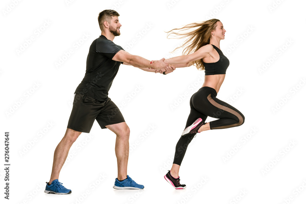 Side view of happy athletic couple training on white background