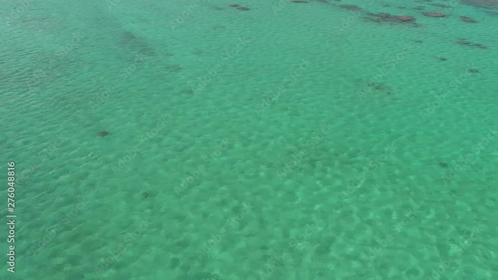 Aerial view of Lanikai beach, Honolulu, Hawaii, low angle view with drone camera moving forward, canoe in clear green open waters Aerial view of Lanikai beach, Honolulu, Hawaii, low angle view with drone camera moving forward, canoe in clear green open waters