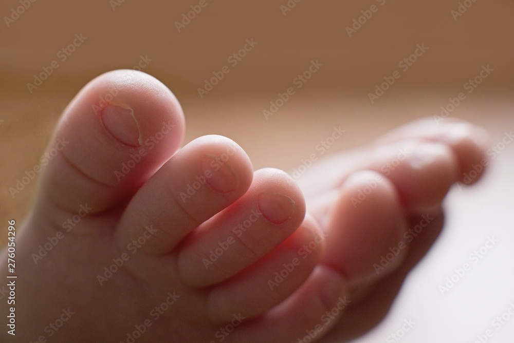 Small legs of the newborn baby in bright light. Gentle fingers standing. New life, the child's birth, the macro picture, selective focus, the place for the text Small legs of the newborn baby in bright light. Gentle fingers standing. New life, the child's birth, the macro picture, selective focus, the place for the text