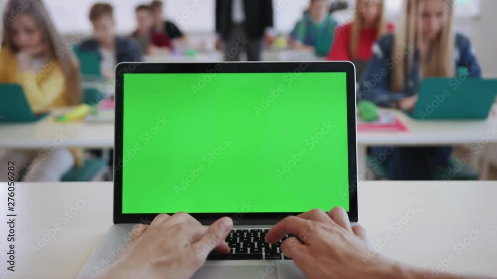 Teacher using a computer laptop with greenscreen mockup sitting in ...