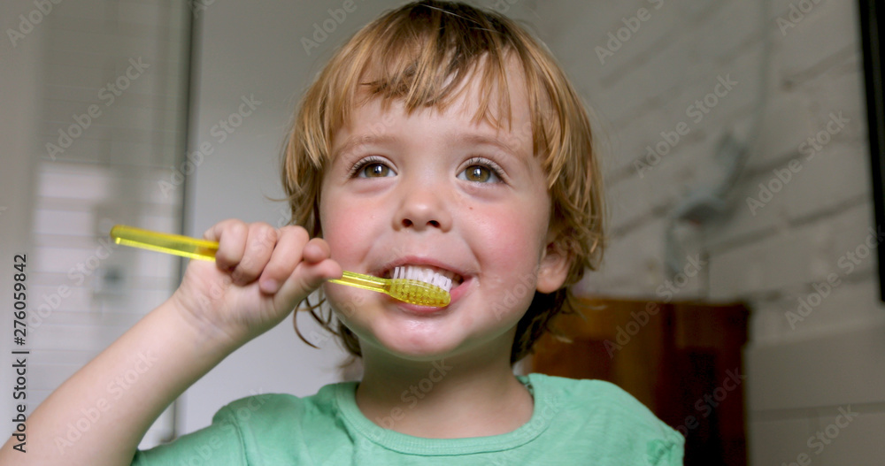 Little blond boy learning brushing his teeth in domestic bath. Kid learning how to stay healthy. Health care concept Little blond boy learning brushing his teeth in domestic bath. Kid learning how to stay healthy. Health care concept