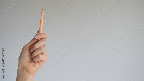 Woman's hand holding a wooden color pencil on isolated background photo