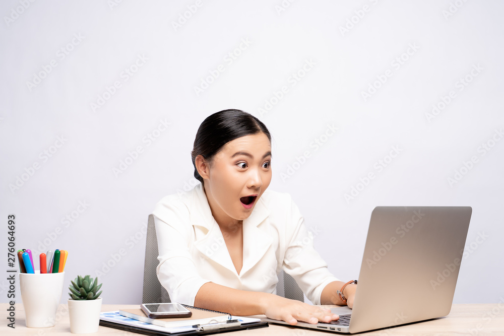 Portrait of a excited woman sitting at office isolated over background Portrait of a excited woman sitting at office isolated over background