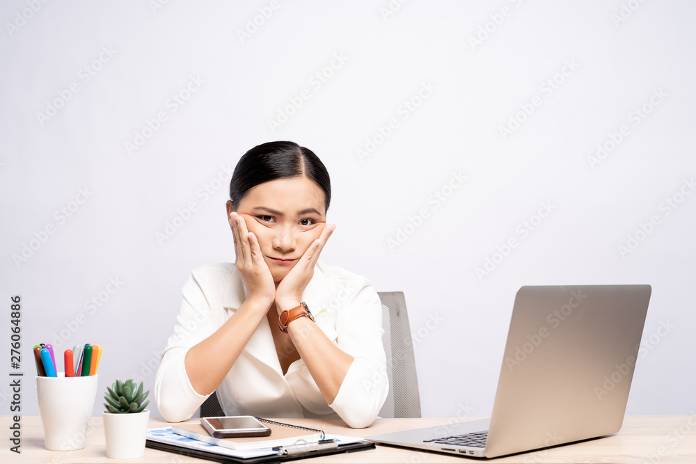 Bored woman at office working with a laptop isolated over background Bored woman at office working with a laptop isolated over background