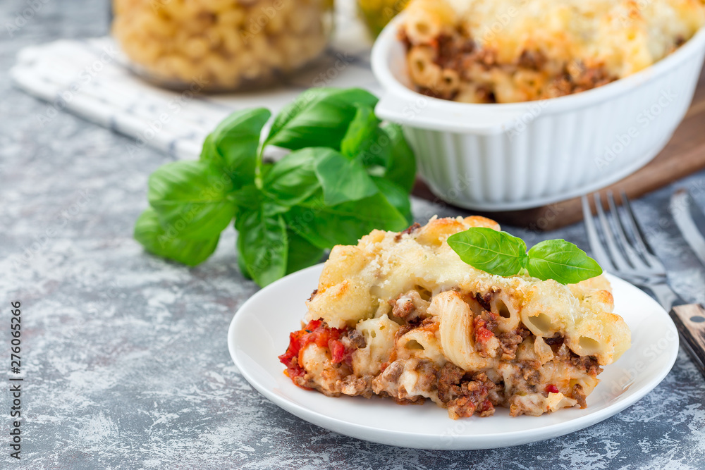 Macaroni casserole with ground beef, cheese and tomato on  white plate, horizontal, copy space