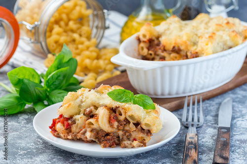 Macaroni casserole with ground beef, cheese and tomato on a white plate, horizontal