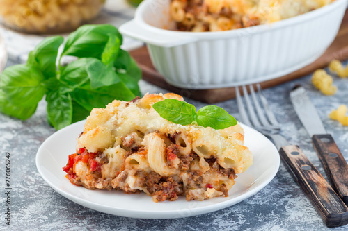 Macaroni casserole with ground beef, cheese and tomato on  white plate, horizontal, closeup