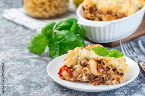 Macaroni casserole with ground beef, cheese and tomato on  white plate, horizontal, copy space