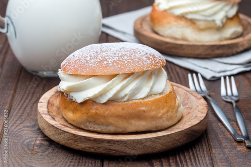 Traditional swedish dessert Semla, also called Shrove bun, with almond paste and whipped cream filling, served with  milk, horizontal