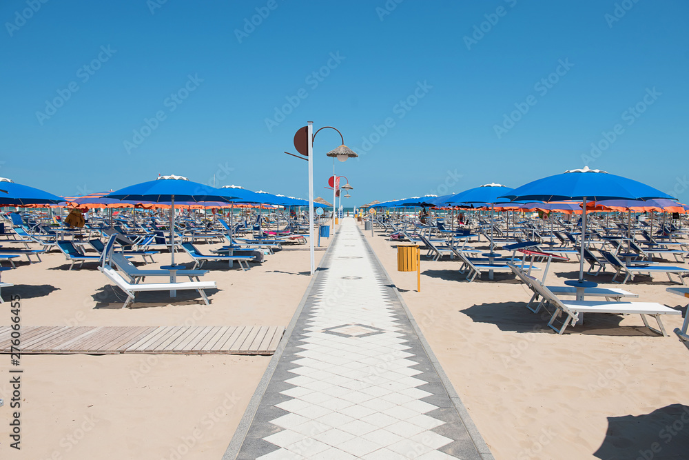 A lot of plastic deckchairs and umbrellas at the sea beach. Empty sand beach. Summer vacation. Italy, Rimimi.