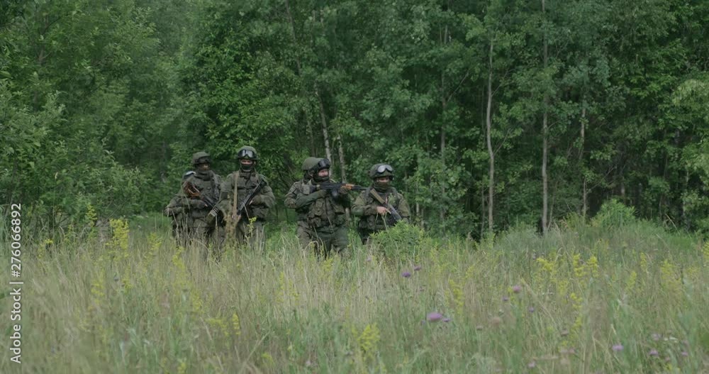 Soldiers in camouflage with assault rifle walking through the field military action in the steppe area, 4k slow motion. Soldiers in camouflage with assault rifle walking through the field military action in the steppe area, 4k slow motion.