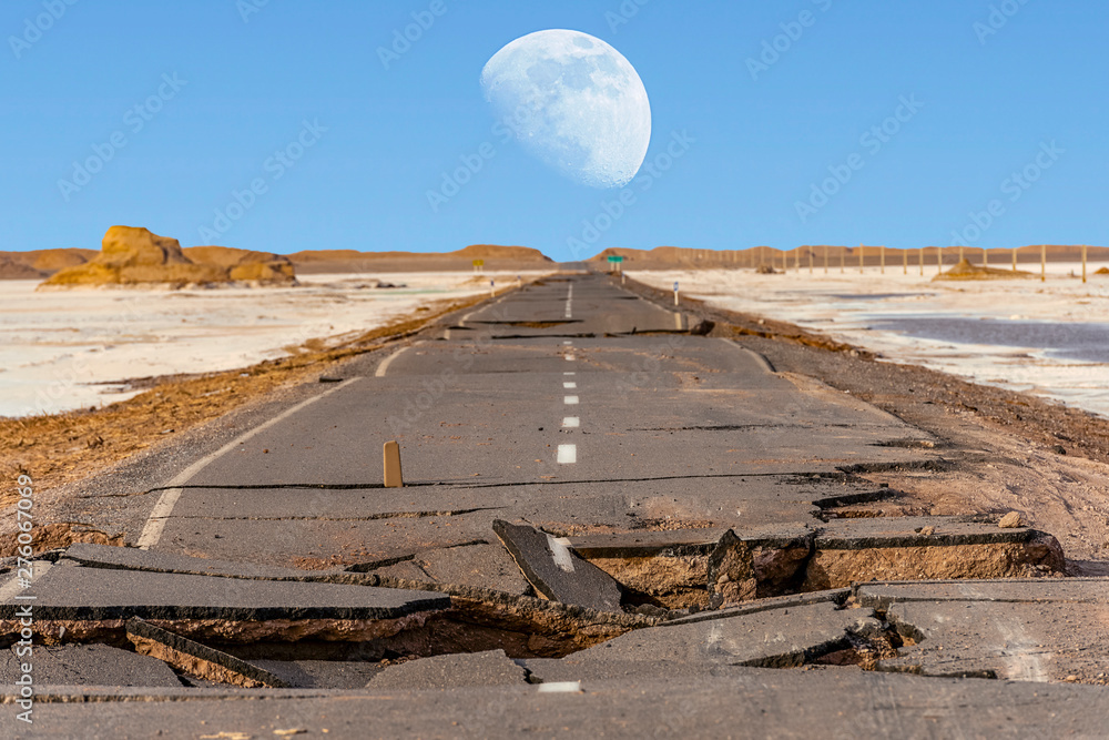 broken asphalt road with huge moon above Lut desert,hottest desert in the world, also known like Kalut Desert