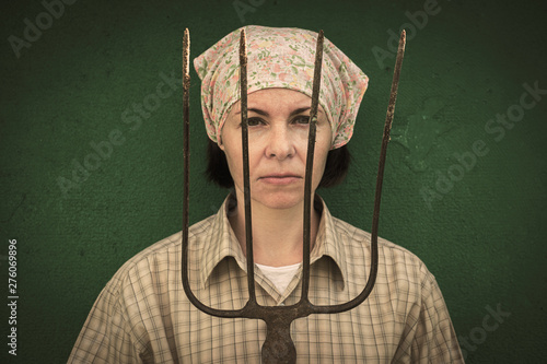 Obraz na plátne Young woman stands with a pitchfork near a stable on a ranch.