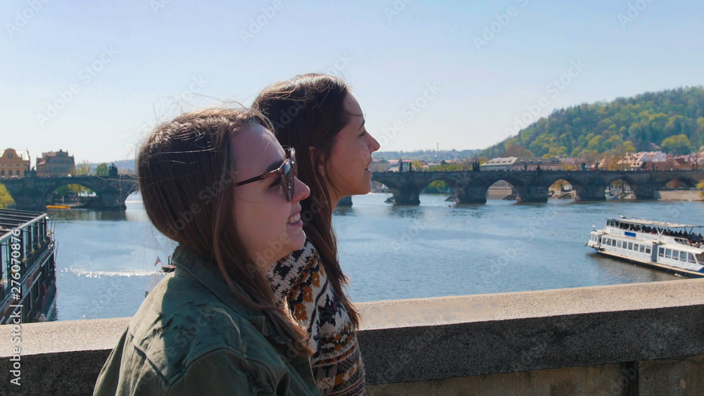 Two young women walking on bridge in the Czech, Prague