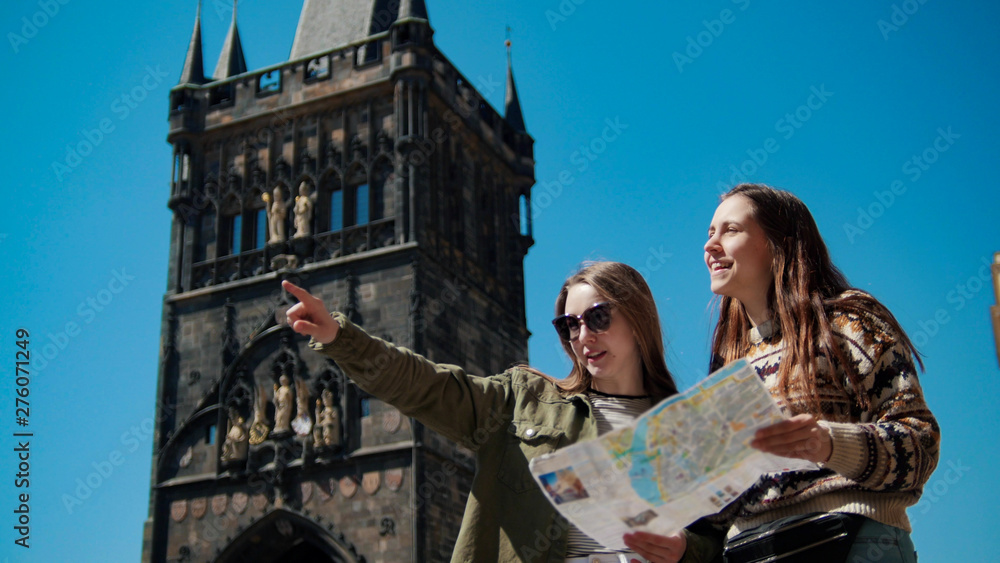 Two young women stand under the old tower and navigat the map